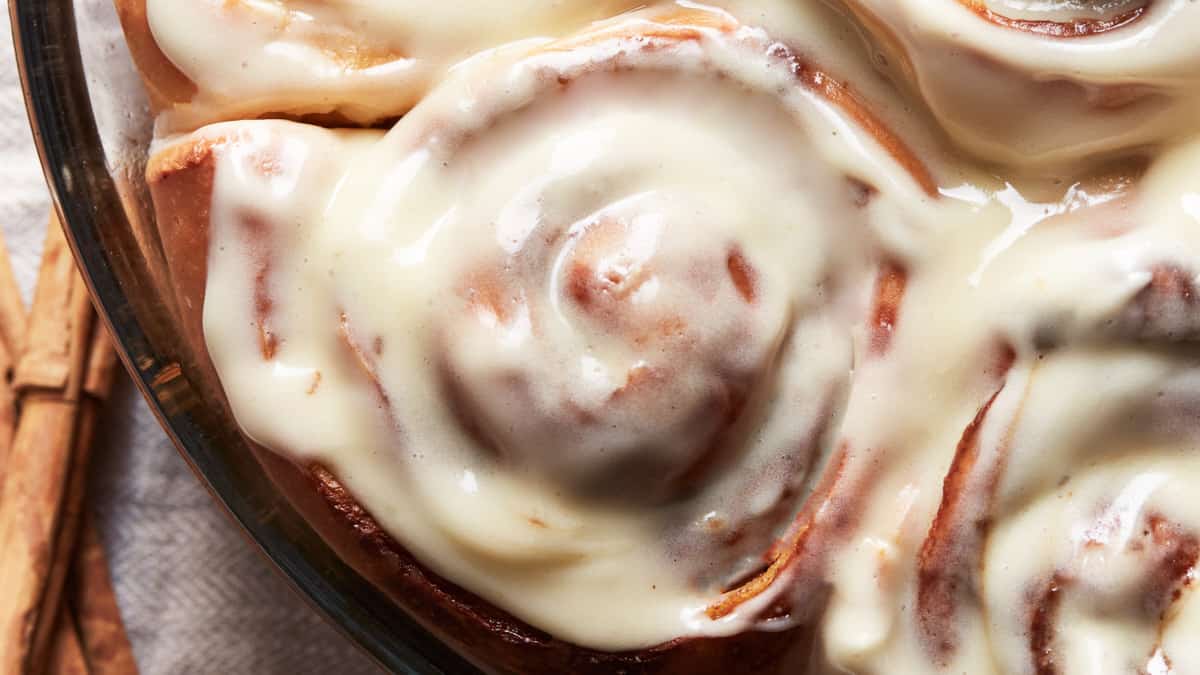 Close up of a cinnamon rolls with cream cheese frosting in a baking dish