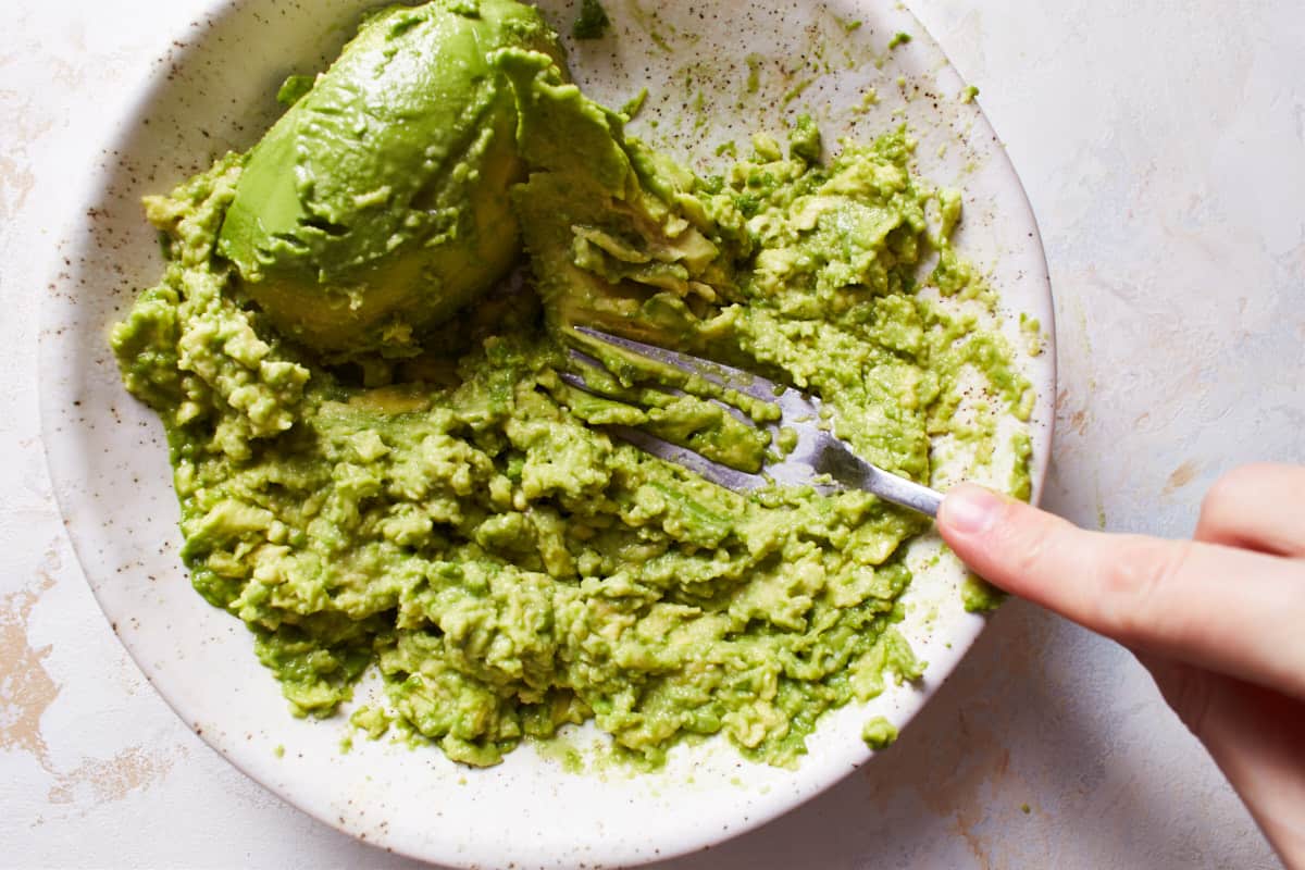 Mashing avocados with a fork in a bowl