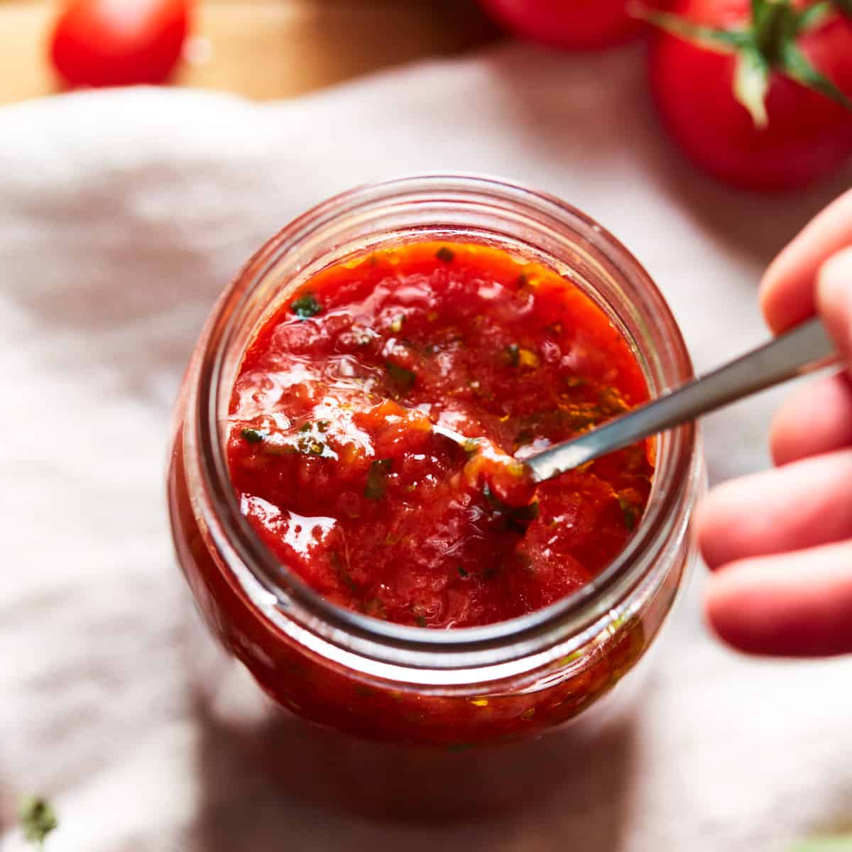 Spooning some pizza sauce out of a jar