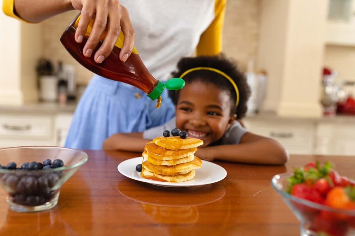 mother putting maple syrup on pancake