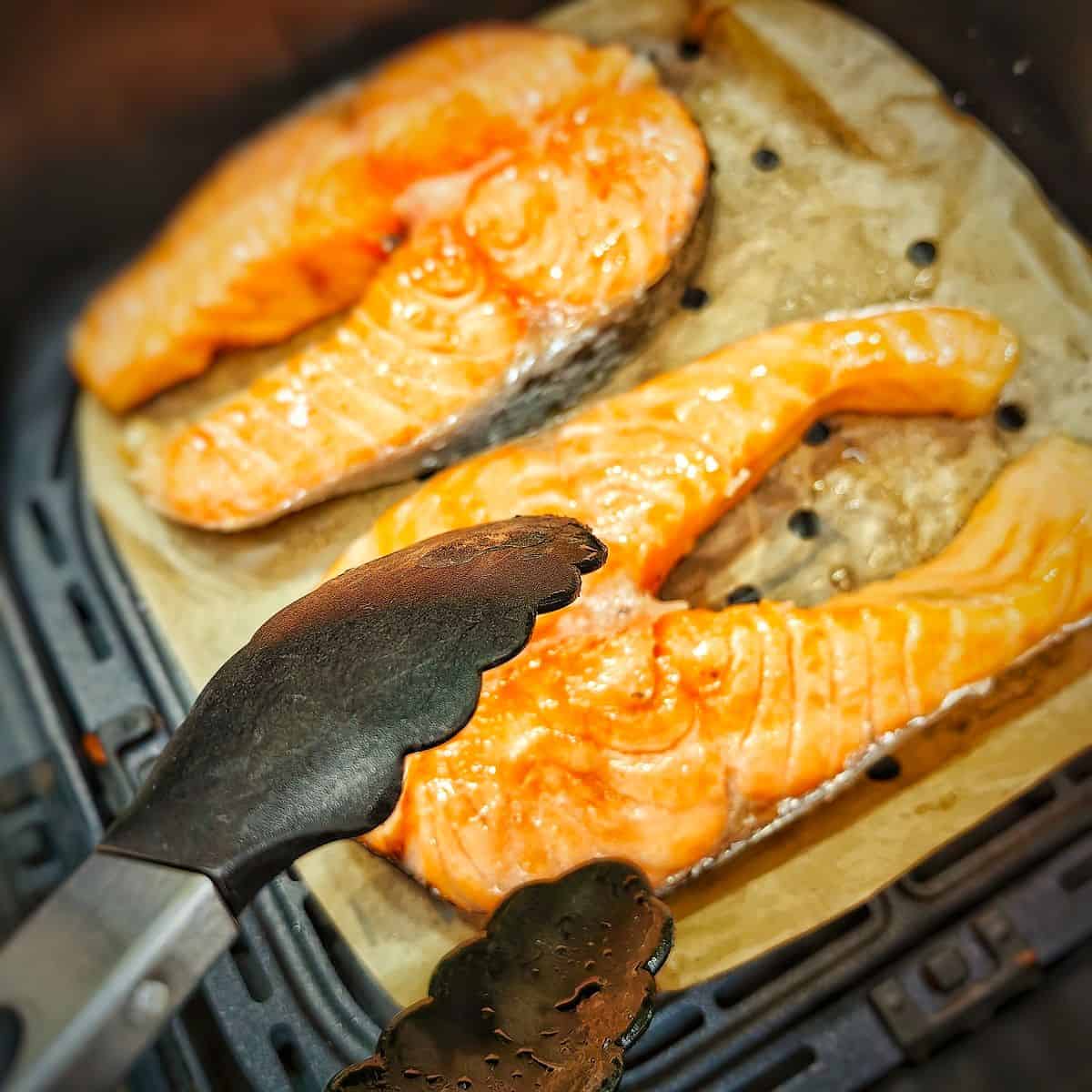 salmon steak with kitchen tongs