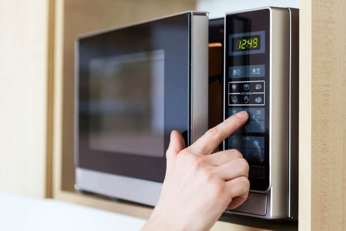 hand using a pushing buttons on microwave