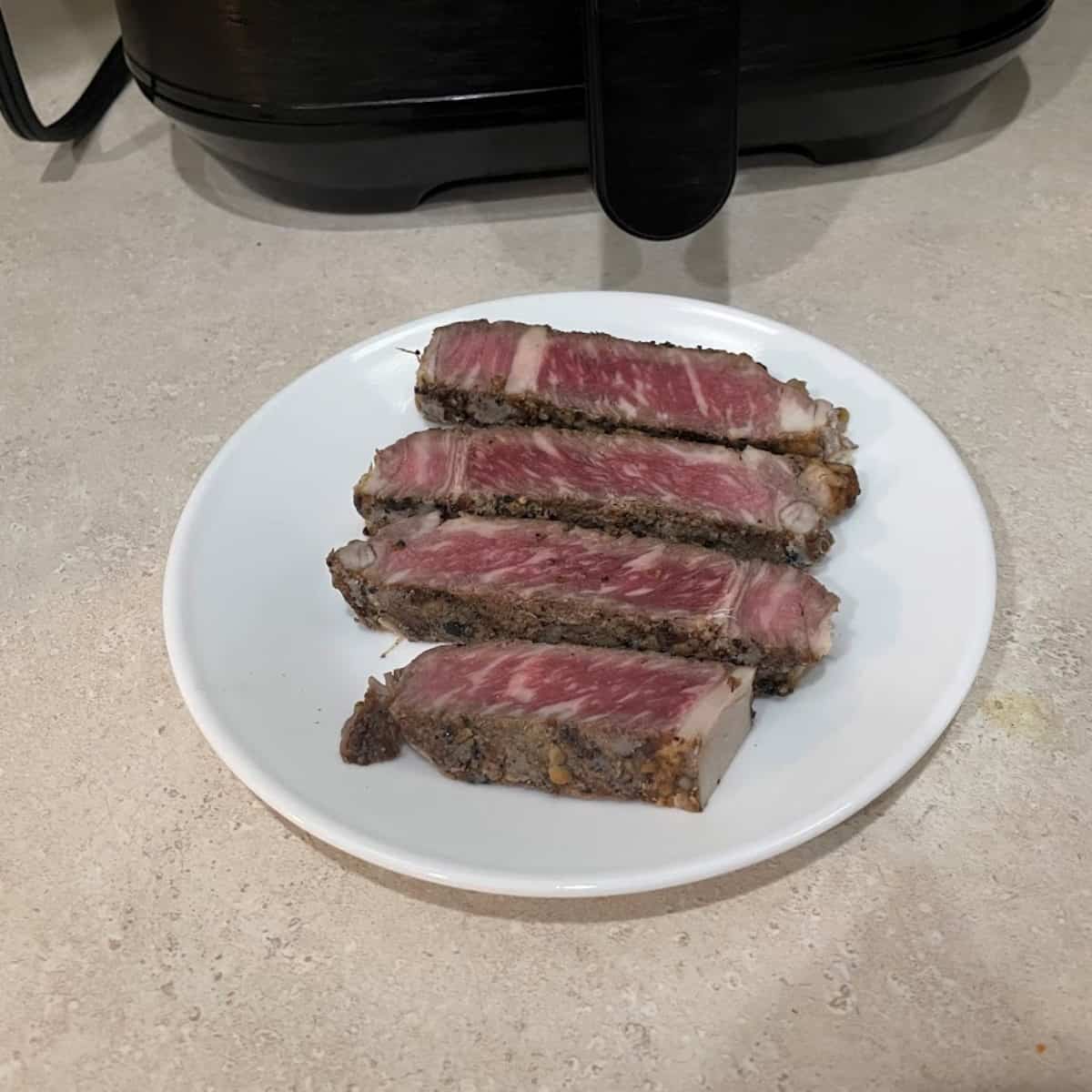 steak on a plate in front of an air fryer