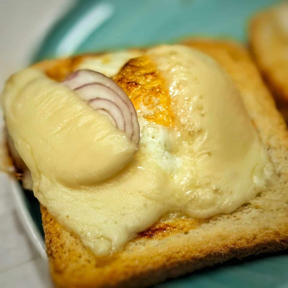 melted cheese, cooked shallot and egg on top of toasted bread