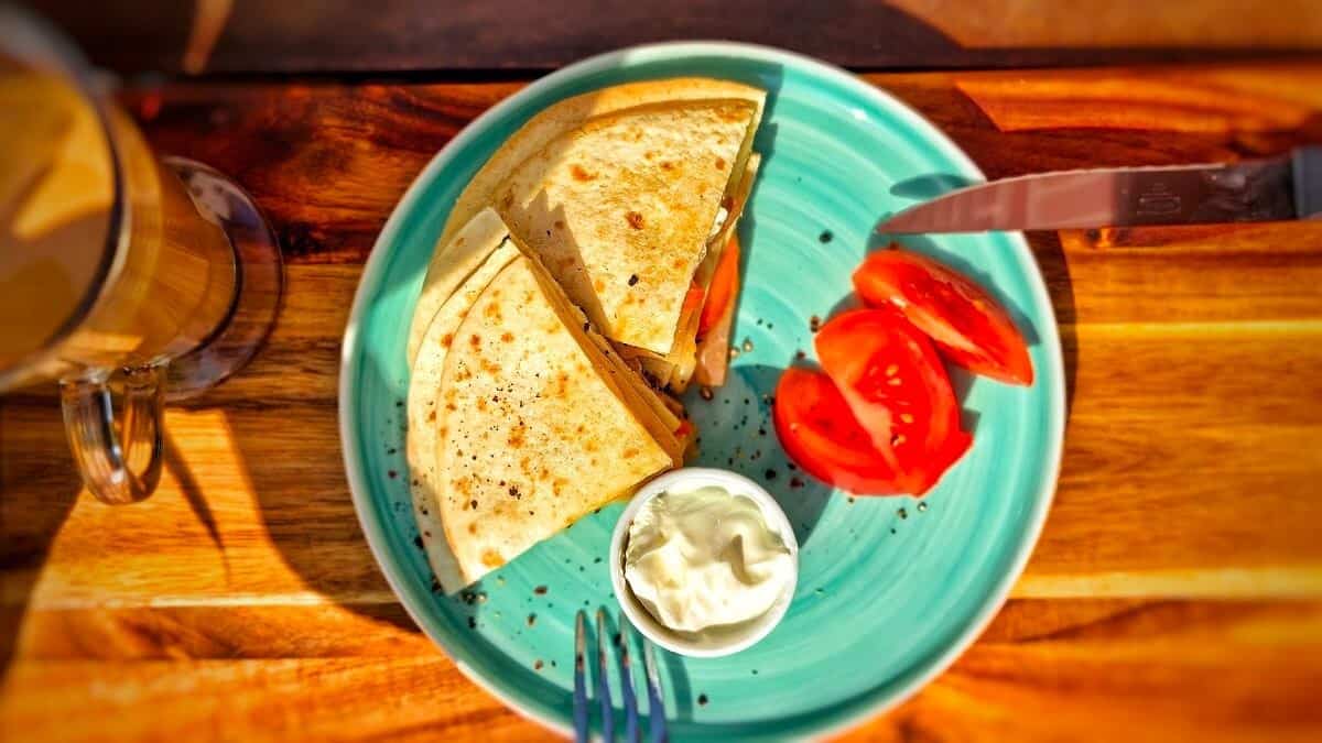 air fryer breakfast tortilla on a serving plate with tomatoes and dip