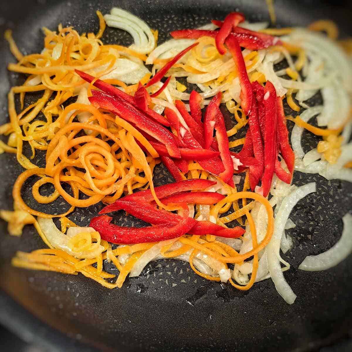 sauteing bell pepper, carrots and onions in a pan