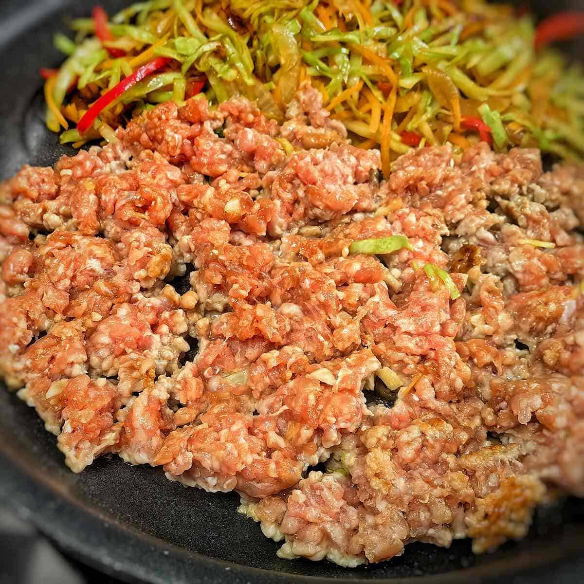 sauteing vegetables and ground pork in a pan