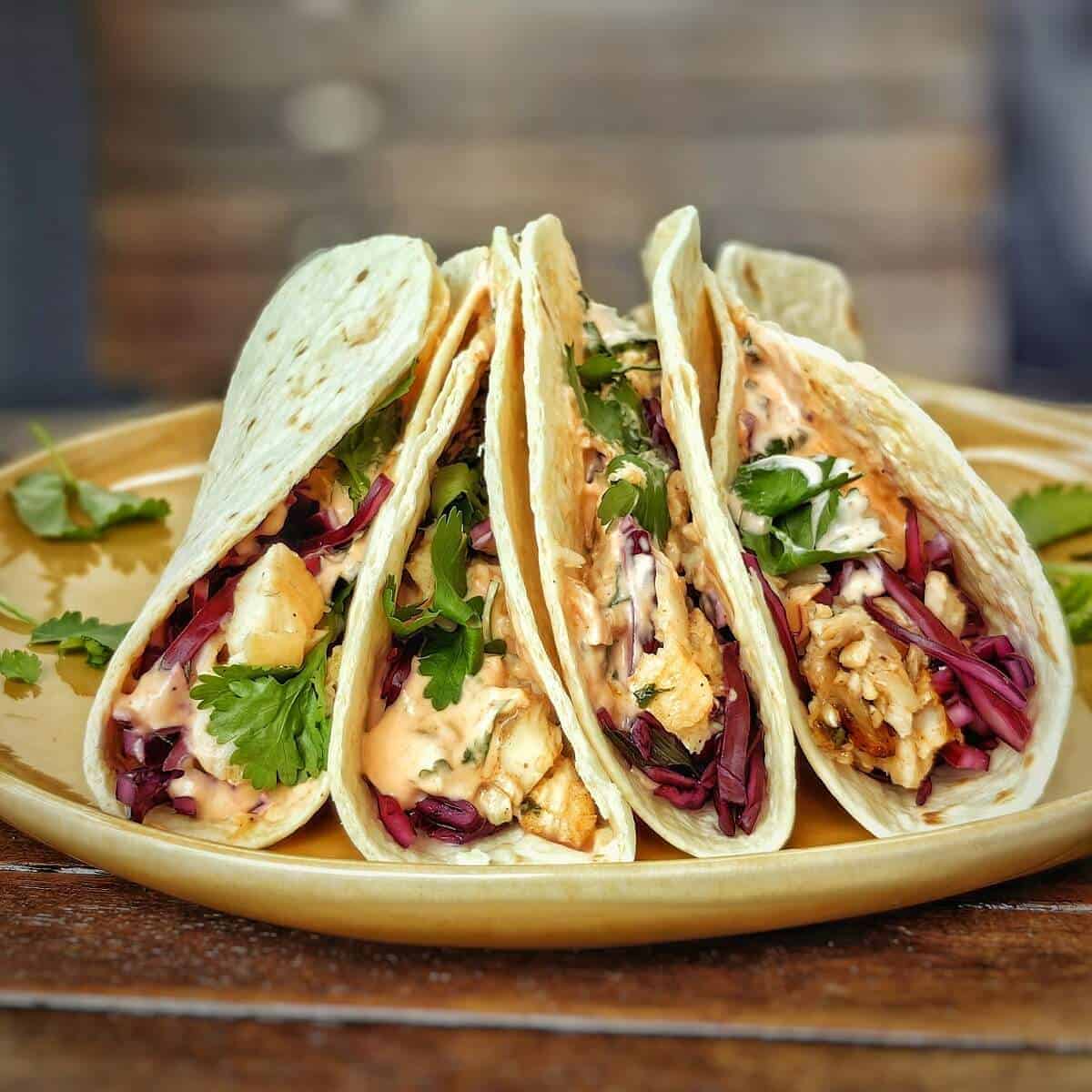 4 air fryer fish tacos lined in a dish with delicious filling