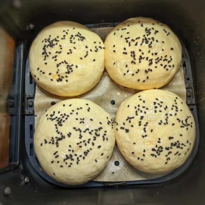 proofed buns with black sesame seeds inside air fryer basket