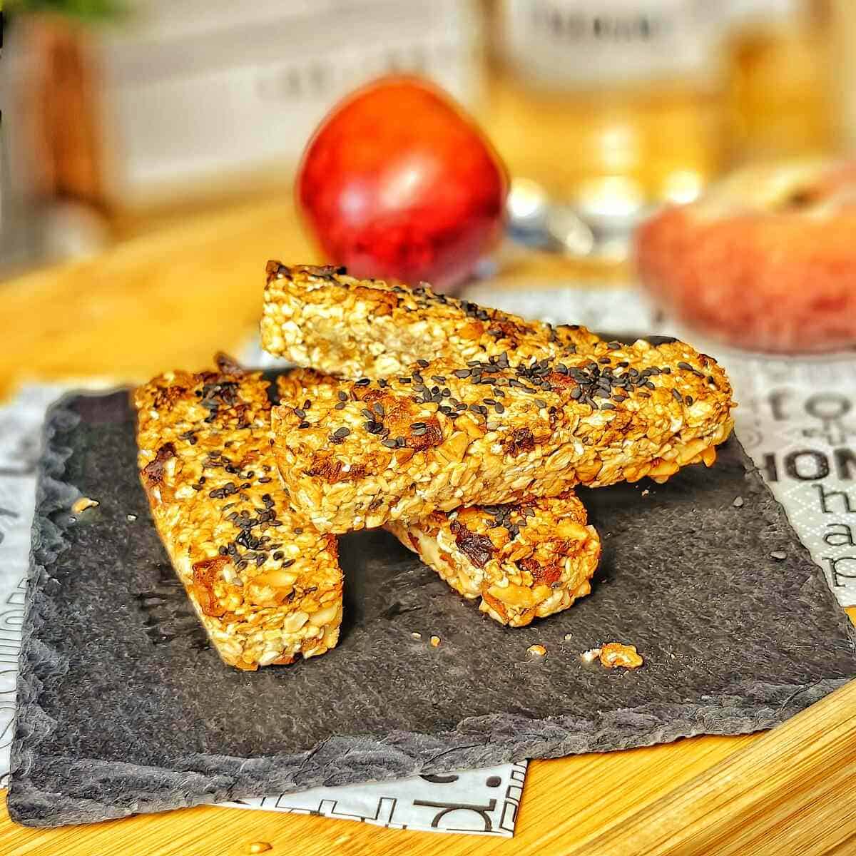 air fryer oatmeal breakfast bars on a black serving plate with apple and peach on the background