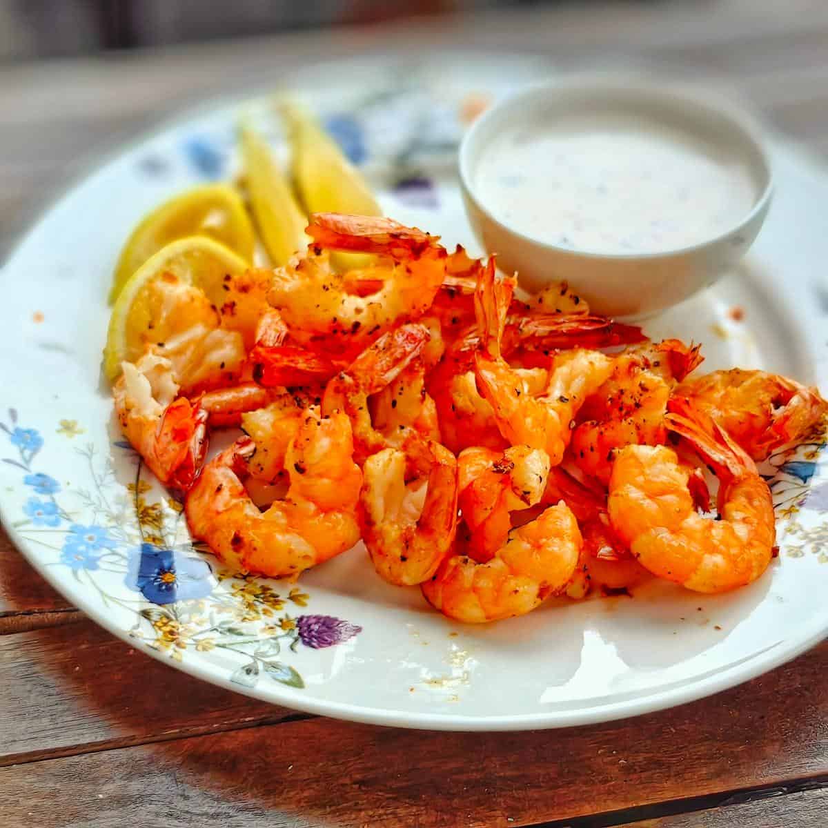 air fryer shrimp with lemon wedges and white sauce`