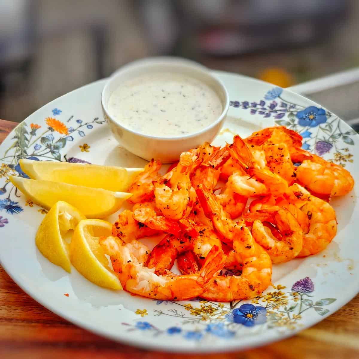 air fryer shrimp with lemon wedges and white sauce on a plate