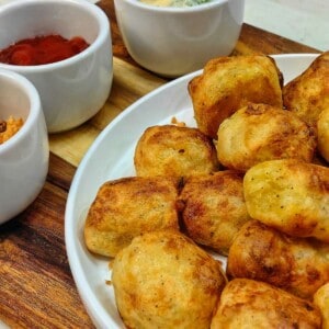 air fryer tater tots on a white serving plate with different dips