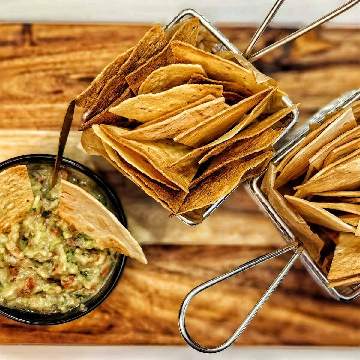 air fryer tortilla chips on wire trays and guacamole in a bowl
