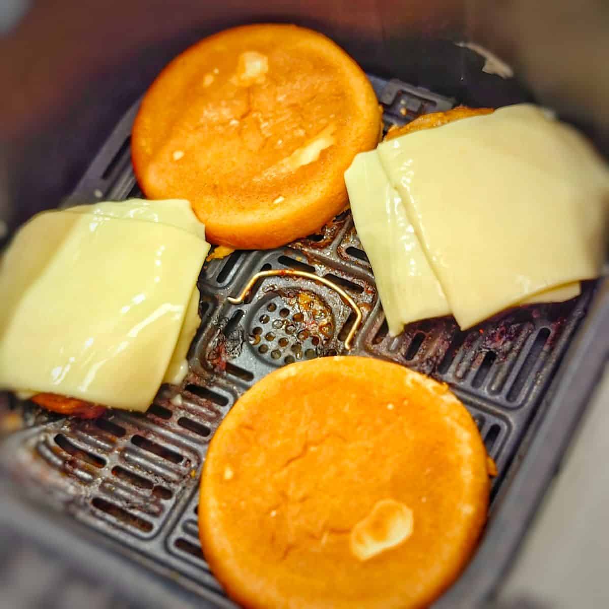 turkey burger paties with buns and cheese in air fryer basket