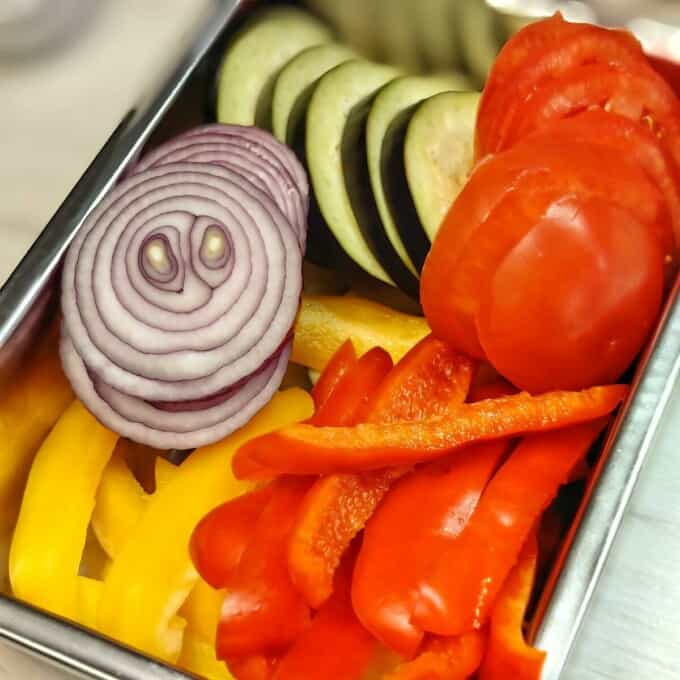 sliced eggplant, onion, and tomato in a metal container