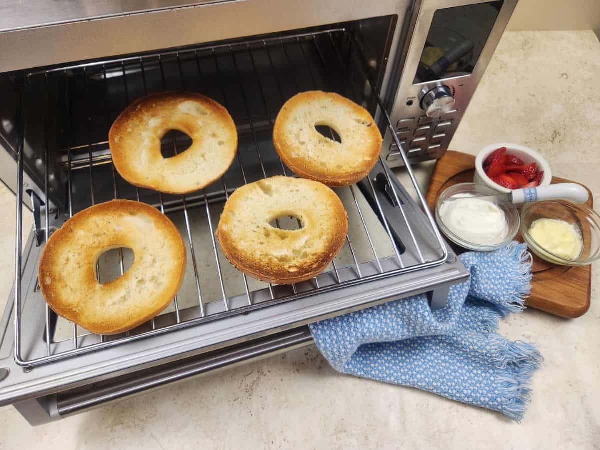 toasted bagels in air fryer oven with different spreads on the side