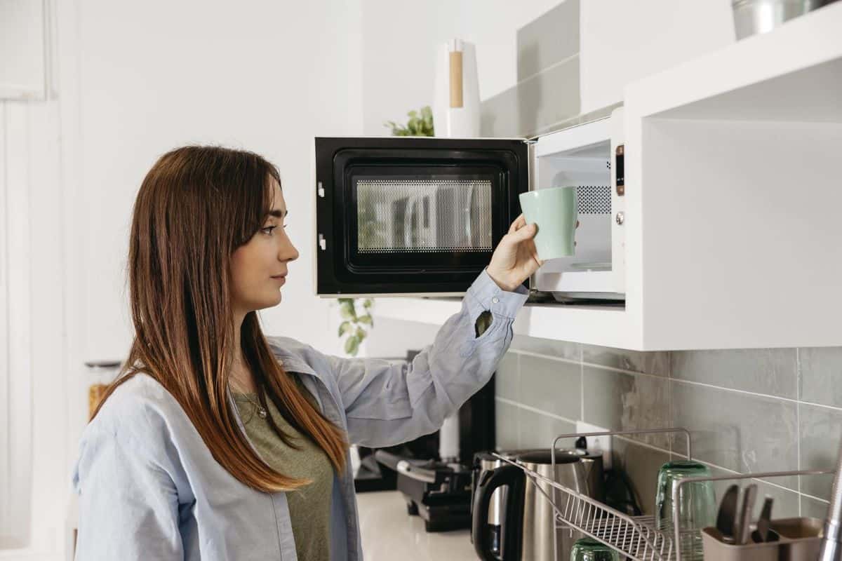 woman putting cup inside microwave
