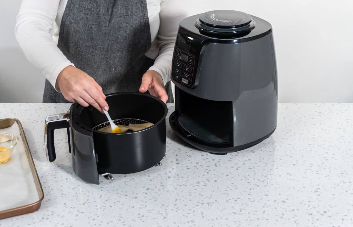 brushing air fryer basket with oil