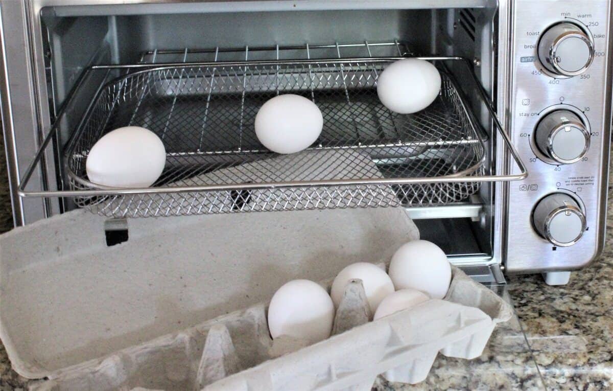 eggs inside air fryer oven with eggs in a carton