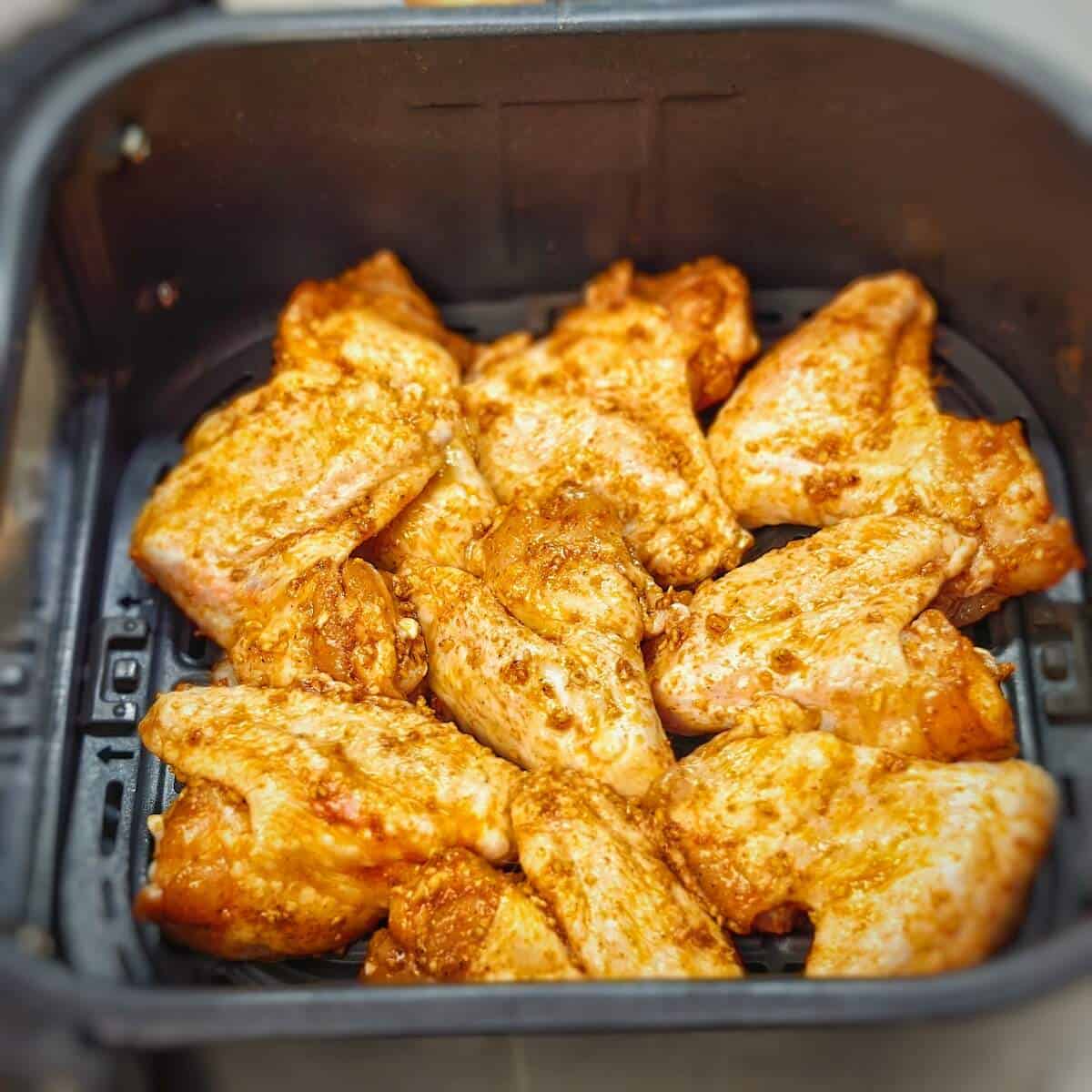 seasoned chicken wings in air fryer basket