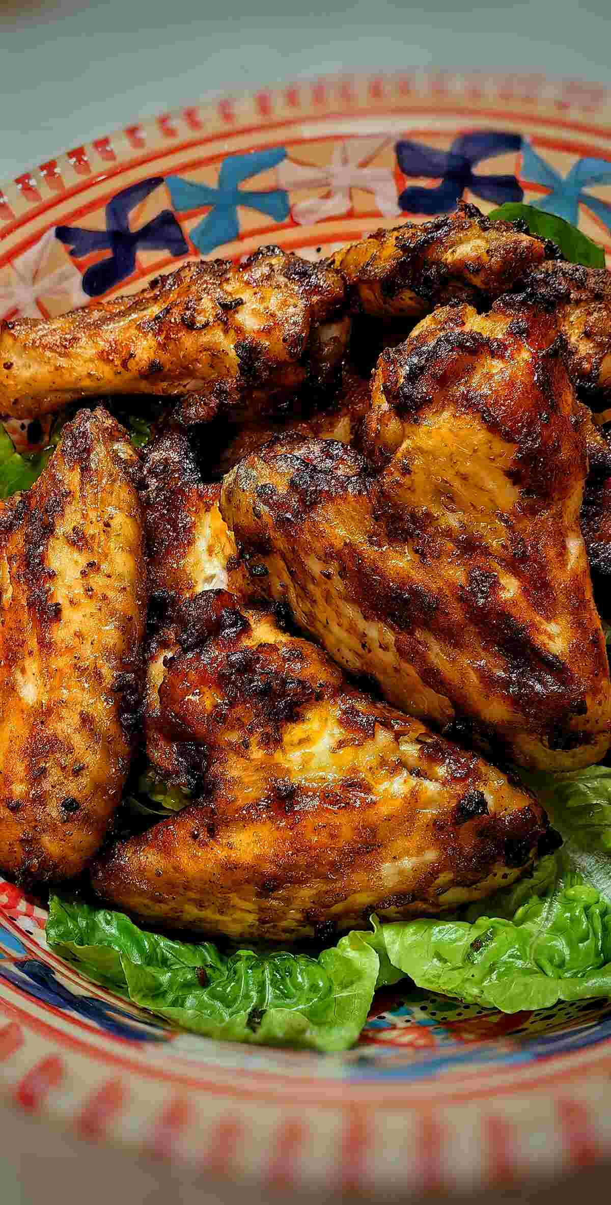 vertical photo of air fryer bbq chiken wings on a bed of greens