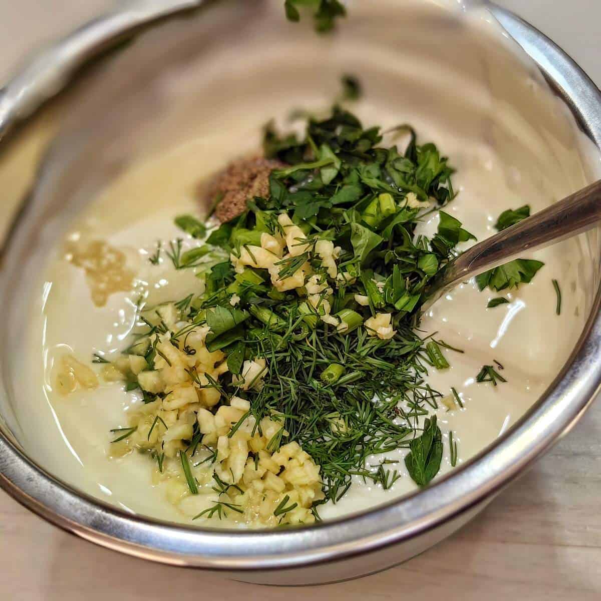 mayonnaise with herbs and spices in a mixing bowl