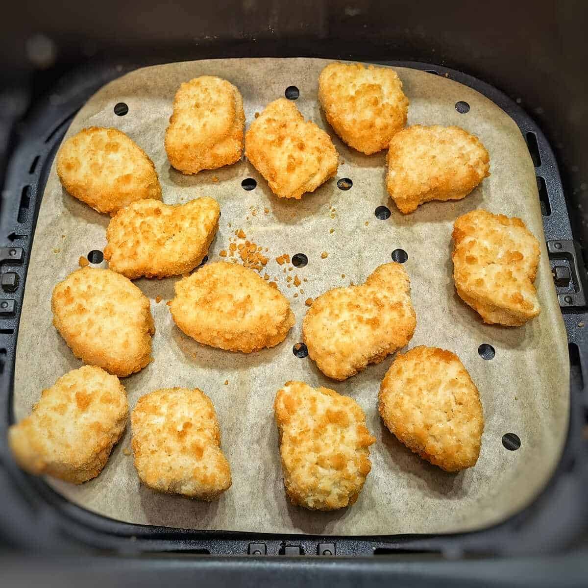 frozen chicken nuggets inside a lined air fryer basket