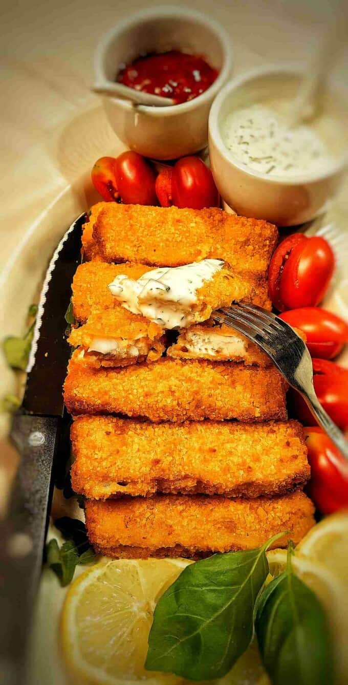 air fryer frozen fish sticks on a serving plate with ranch dip and tomatoes