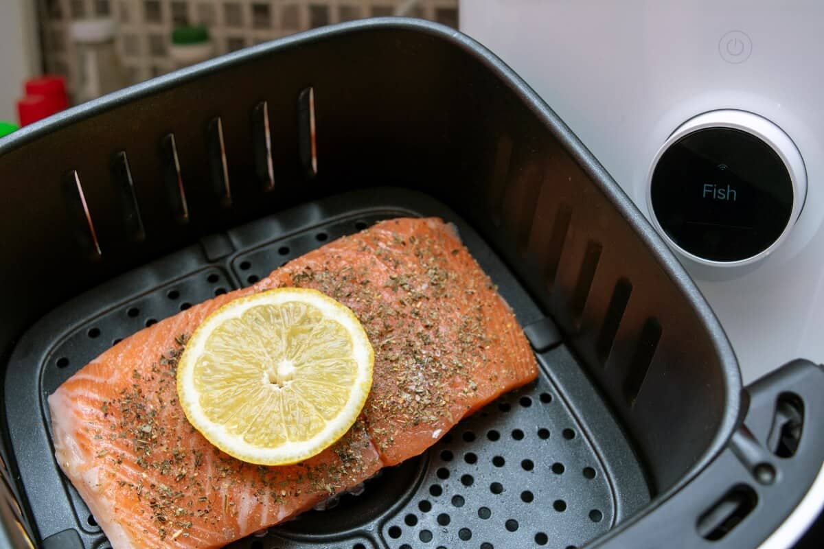 salmon with lemon slice inside air fryer basket