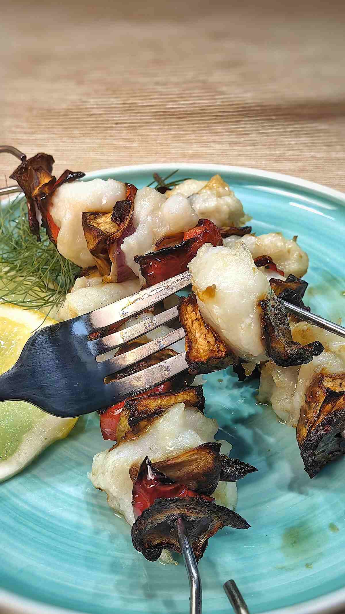 air fryer fish kebabs on a serving dish and with a fork