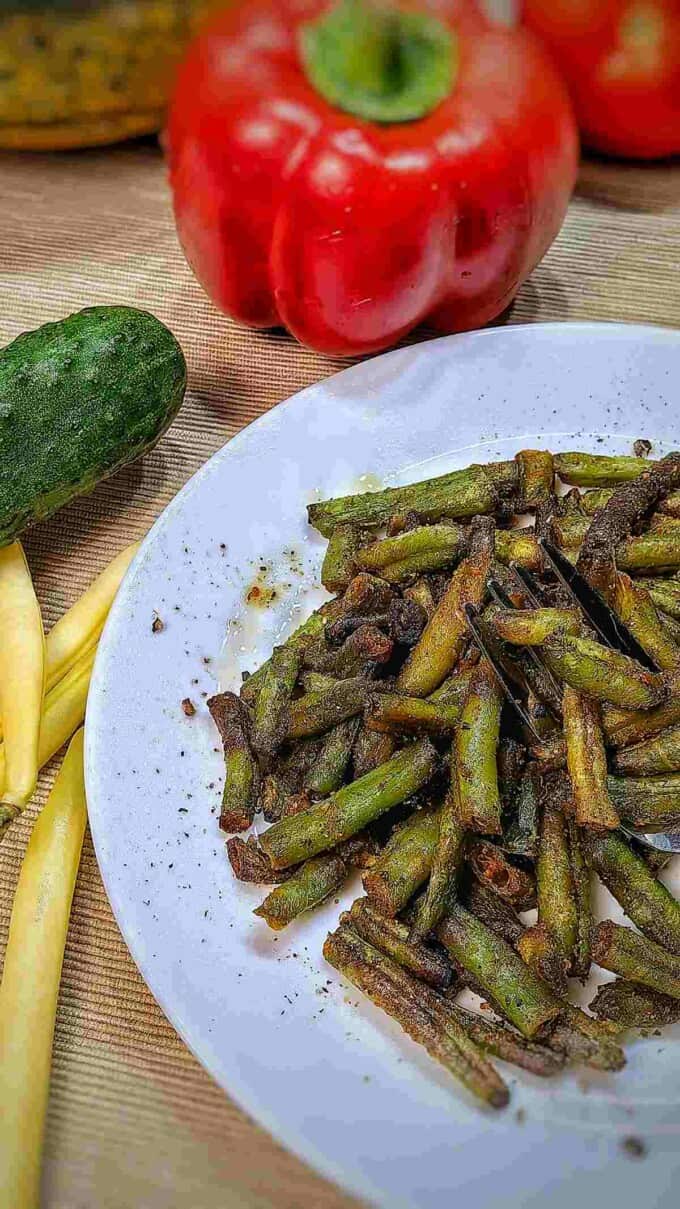 air fried frozen green beans on a serving dish with vegetables surrounding it