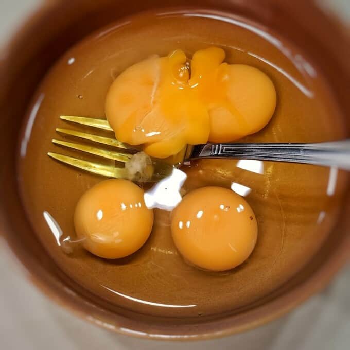 cracked eggs in a bowl with fork