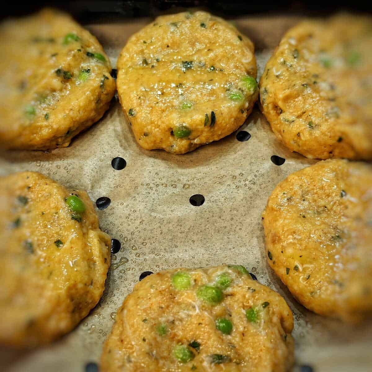 fish cake patties inside air fryer basket with parchment liner
