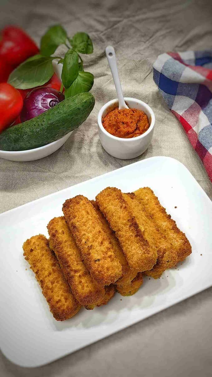 air fryer vegetable fingers on a serving plate with romesco sauce and basket of vegetables