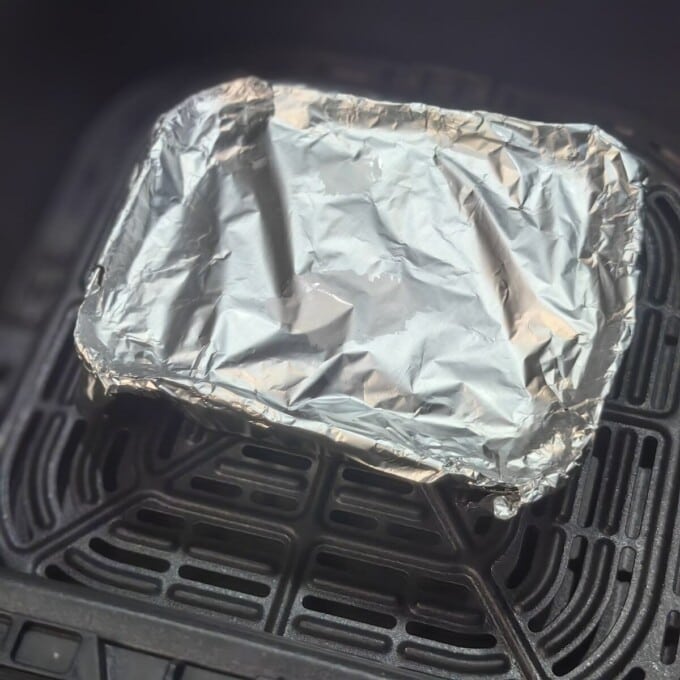 aluminum pan with foil cover inside air fryer basket