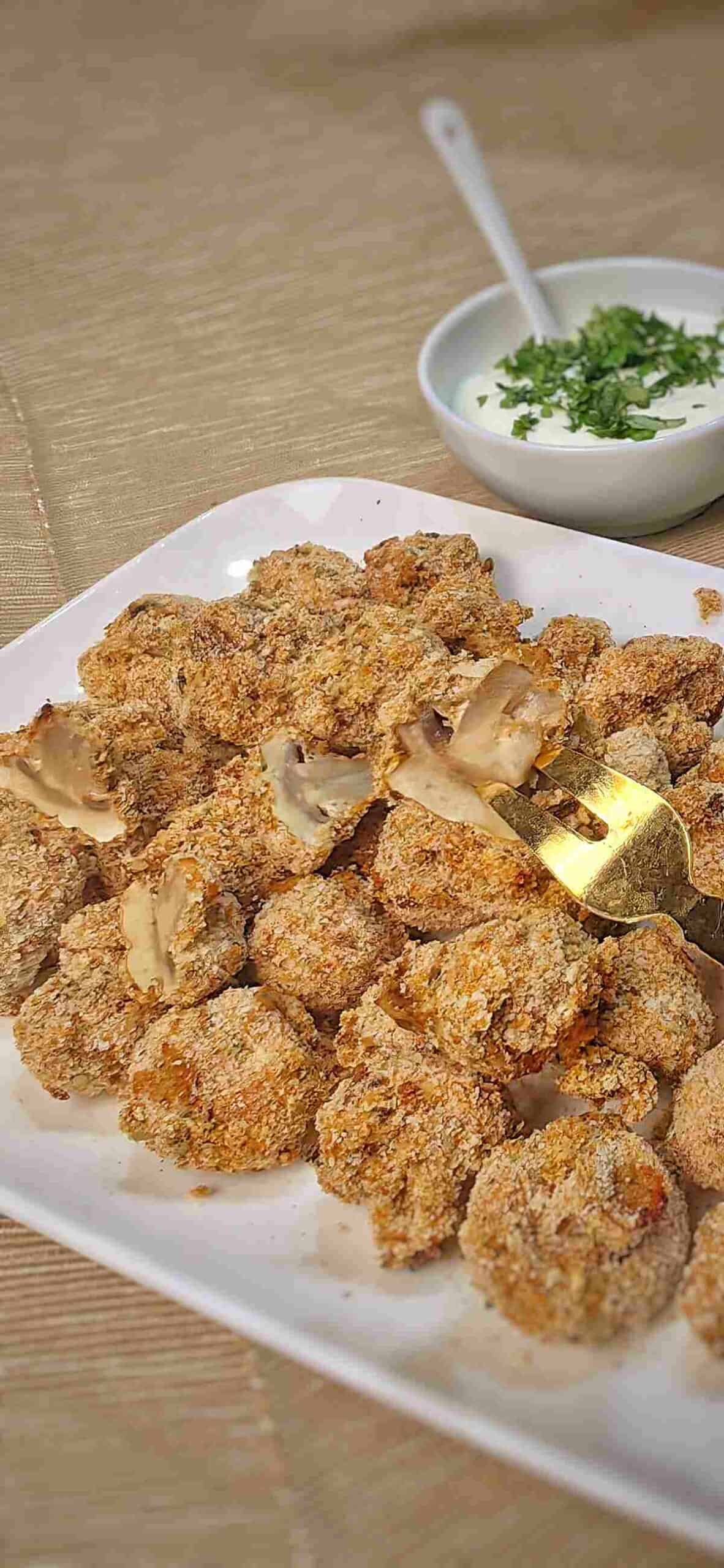 air fried mushrooms on white serving dish with fork and white sauce