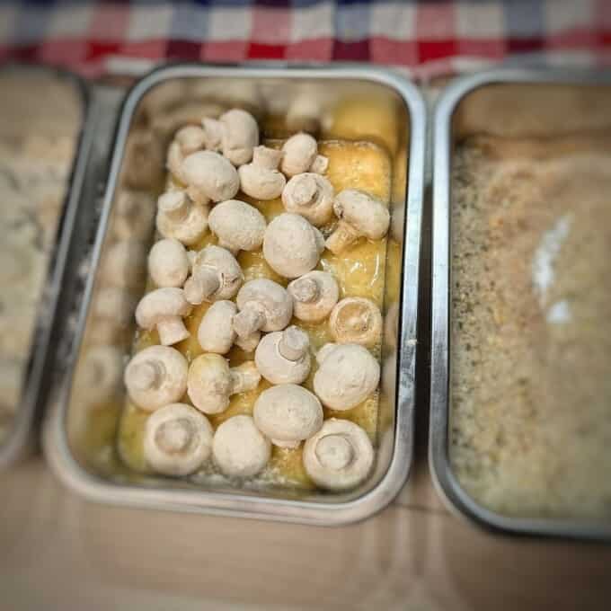 mushrooms in egg, mushrooms rolled in flour, and breadcrumbs in metal container