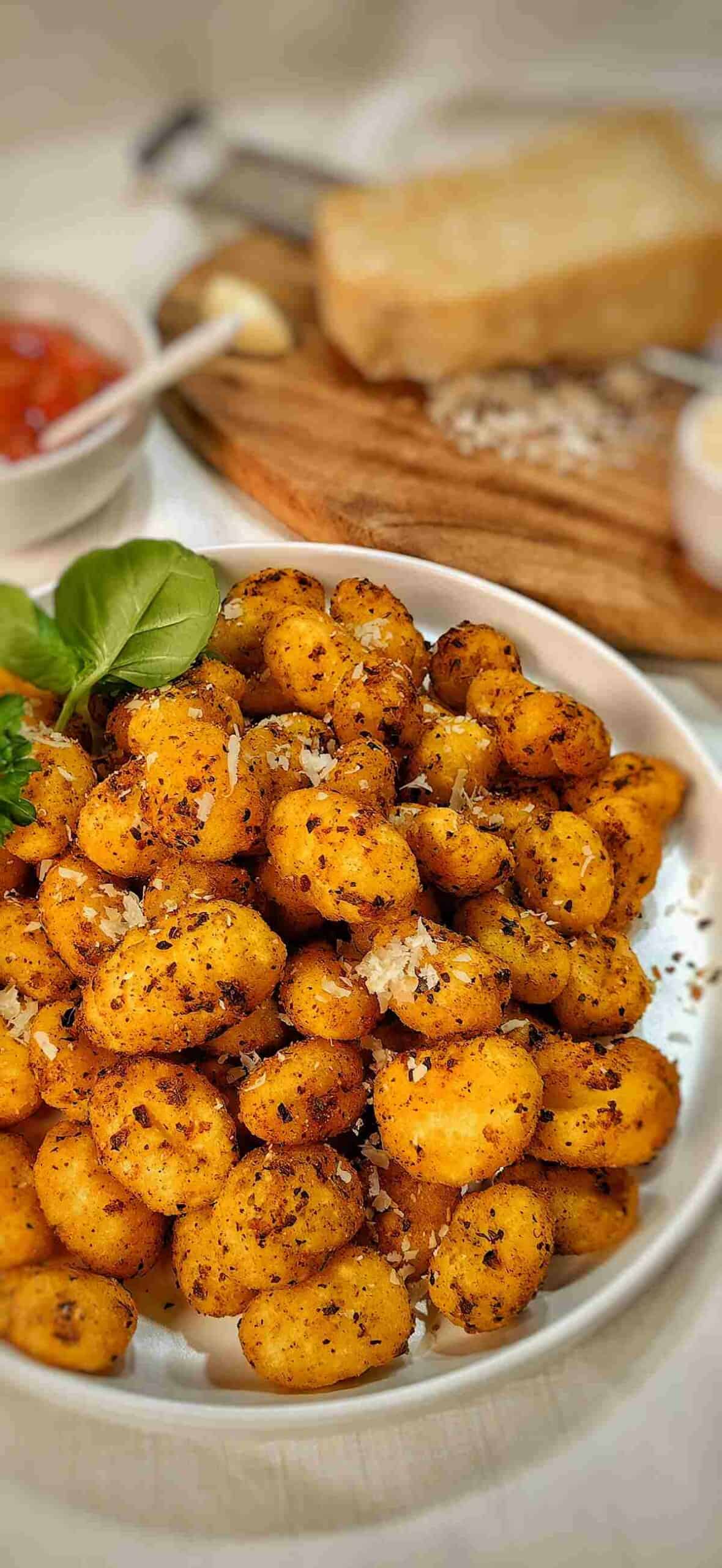 air fried gnocchi on a serving dish with sprinkle of grated Parmesan.