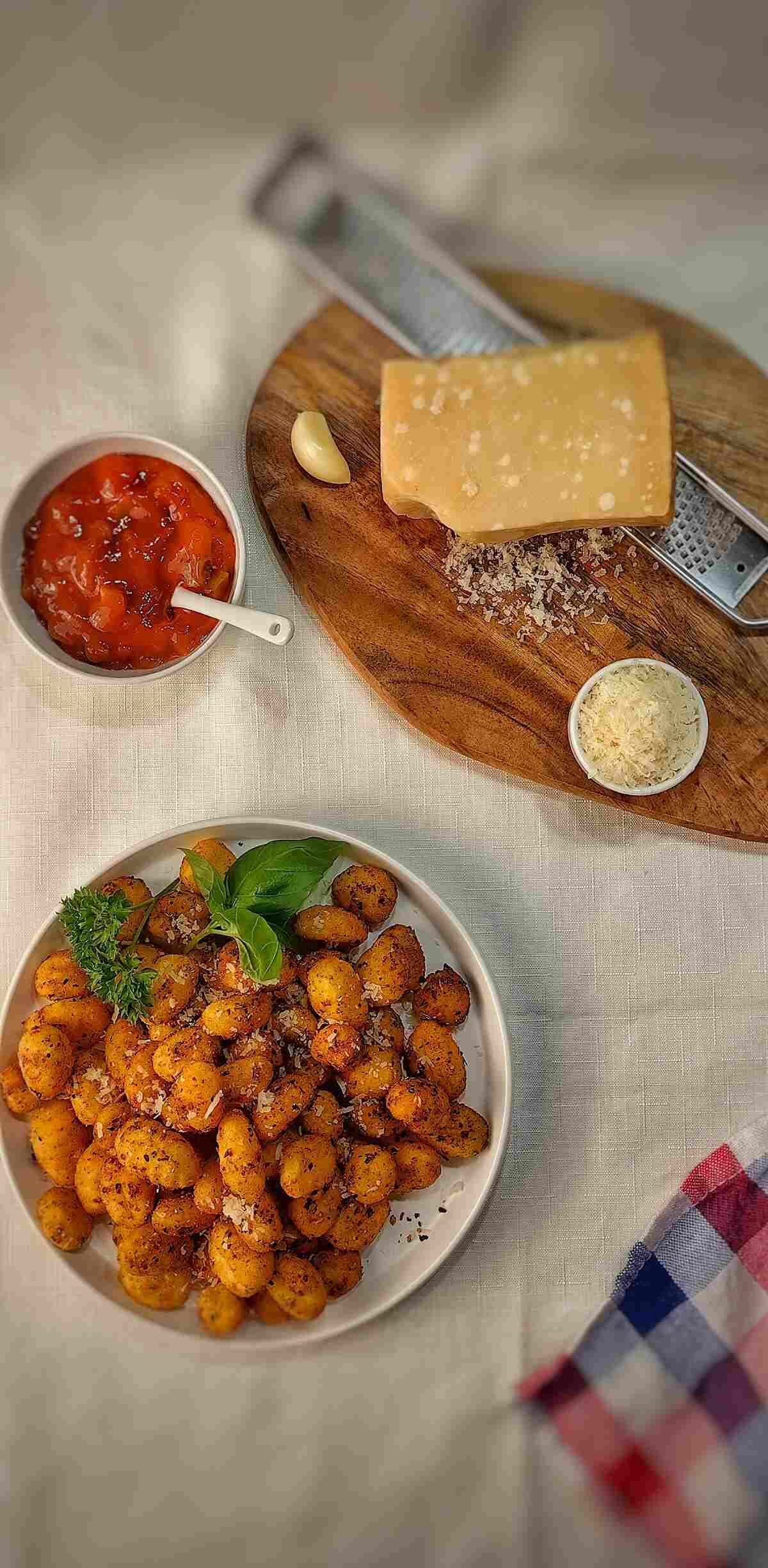 air fried gnocchi on a serving dish with parmesan and red sauce on the side