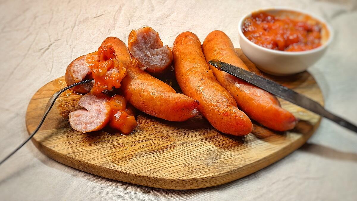 pieces of whole and sliced kielbasa with bowl of sauce
