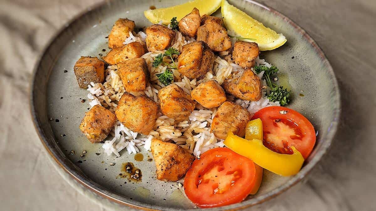 salmon bites with rice and tomato and lemon slices