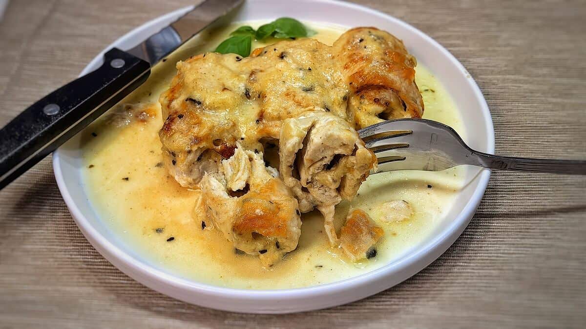 stuffed chicken breast roll-ups on a serving plate with knife and fork