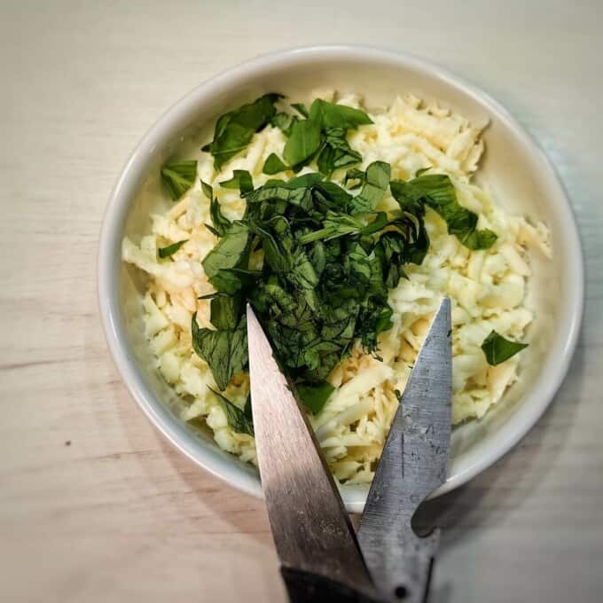 herbs and cheese inside white bowl with scissors