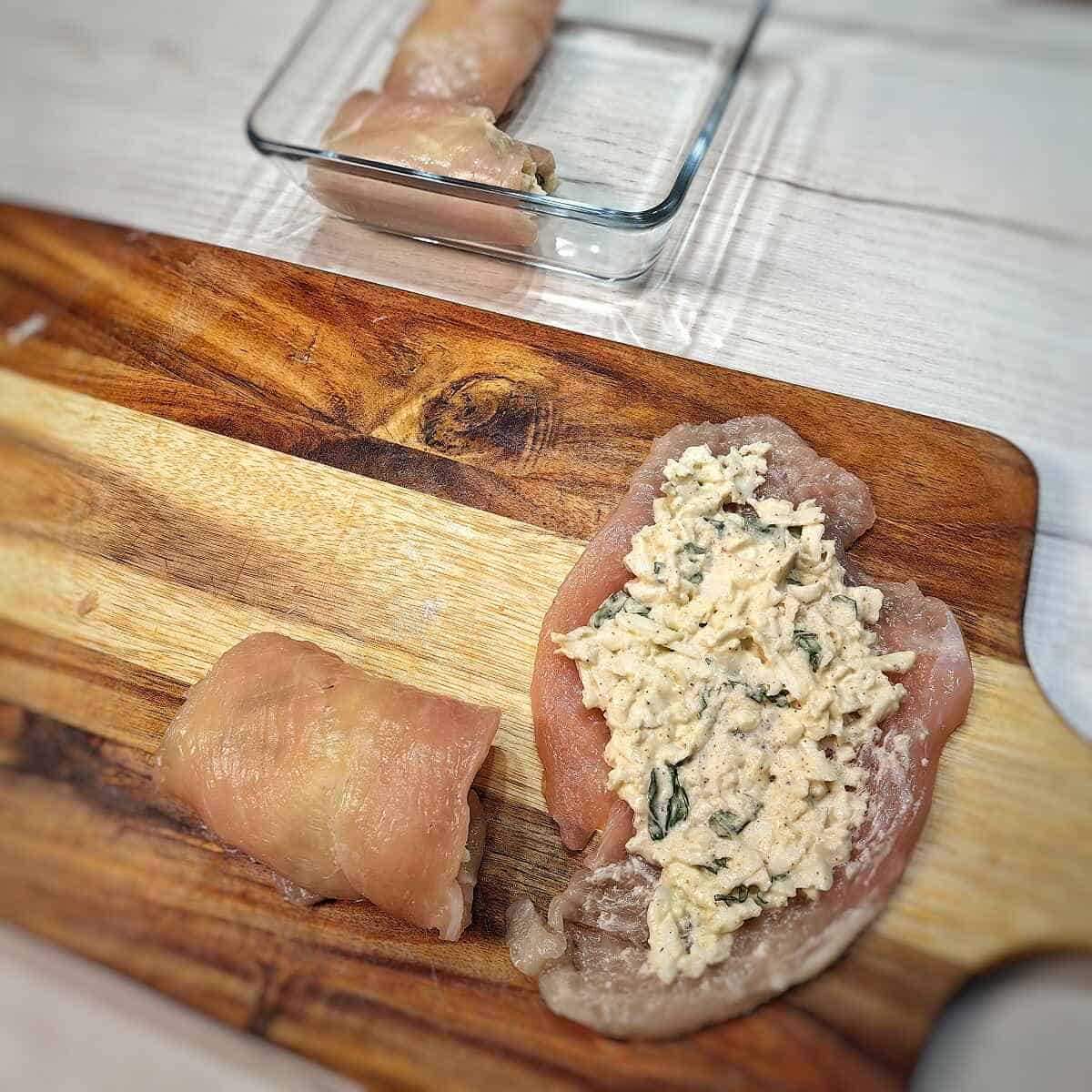 chicken breast with cheese and herb mixture and a rolled up stuffed chicken breast