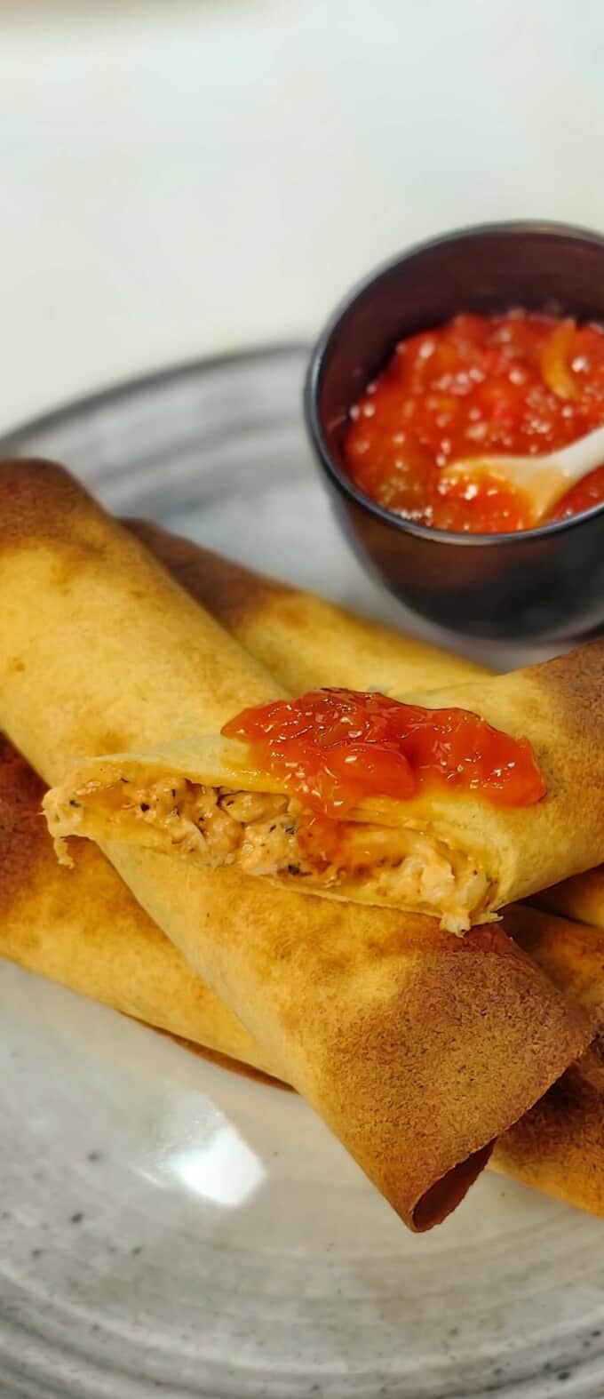 sliced air fryer taquito with red salsa