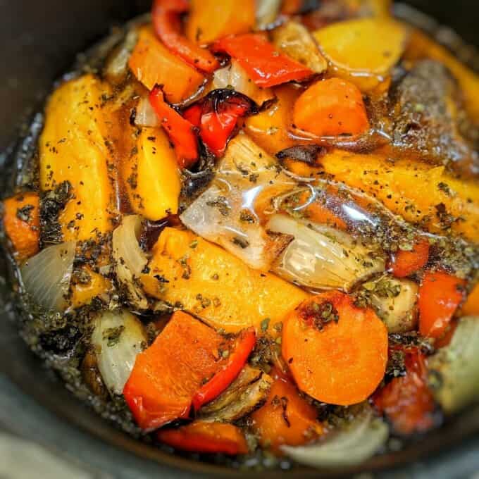 close up of roasted vegetables with broth inside pot