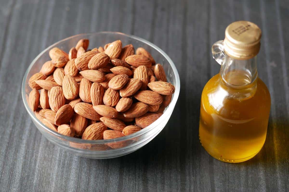 almond nuts in a bowl and almond oil in a jar on table