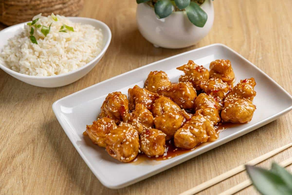 caramelized sesame chicken and rice on wooden table