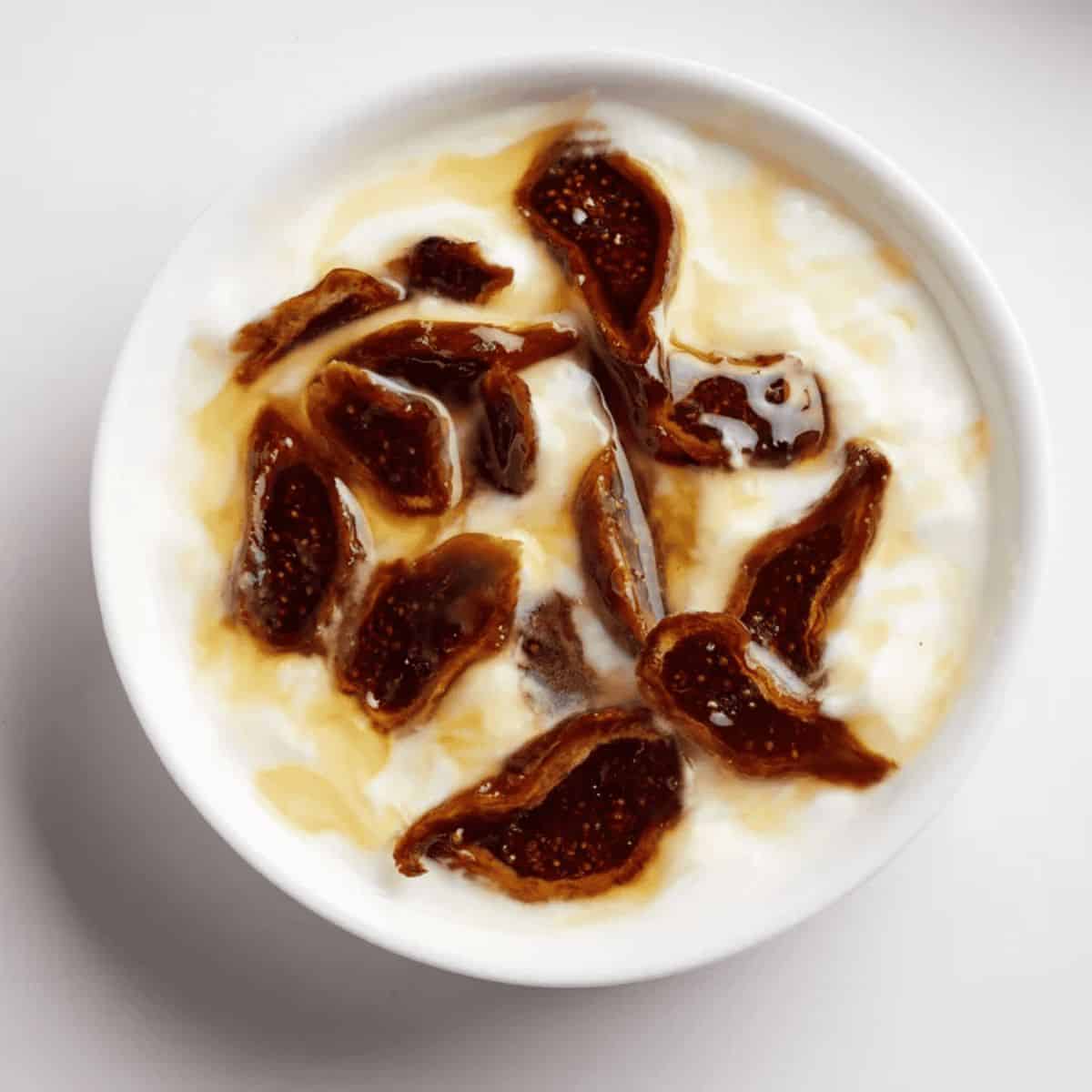 A bowl of fig and honey yogurt, featuring creamy yogurt topped with sliced figs and a drizzle of golden honey.